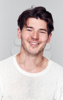 Studio Portrait Of Young Man Wearing White T Shirt Smiling At Camera