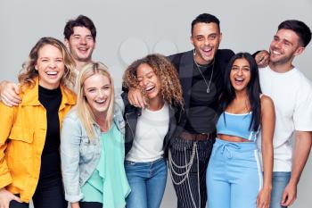 Group Studio Shot Of Young Multi-Cultural Friends Smiling And Laughing At Camera