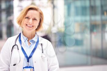 Portrait Of Female Doctor With Stethoscope Wearing White Coat Standing In Modern Hospital Building