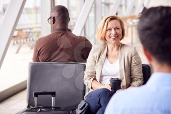 Mature Businesswoman Waiting In Airport Departure Lounge Drinking Coffee From Reusable Cup