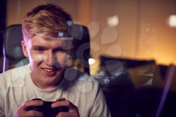 Teenage Boy With Game Pad Sitting In Chair and Gaming At Home With Screen Reflection