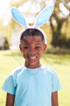 Portrait Of Boy Wearing Bunny Ears On Easter Egg Hunt In Garden