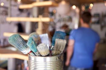 Close Up Of Brushes In Workshop Of Couple Upcycling Furniture