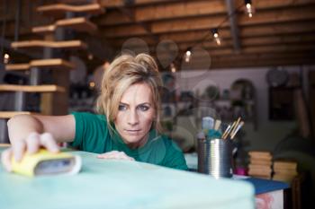 Woman In Workshop Upcycling And Working On Furniture With Sandpaper