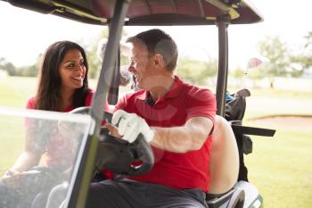 Mature Couple Playing Golf Driving Buggy Along Course To Green On Red Letter Day