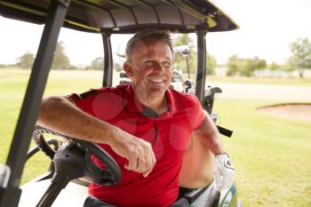 Mature Man Playing Golf Driving Buggy Along Course To Green On Red Letter Day