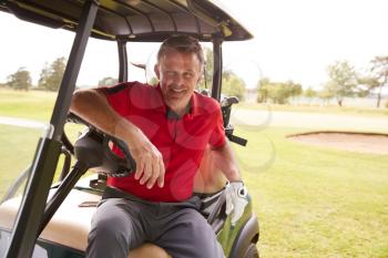 Portrait Of Mature Man Playing Golf Driving Buggy Along Course To Green On Red Letter Day