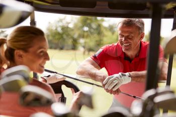 Couple Playing Golf Driving Buggy And Talking Over Clubs