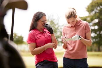 Two Women Playing Golf Marking Scorecard With  Buggy In Foreground