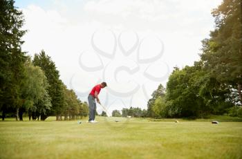 Mature Male Golfer Preparing To Hit Tee Shot Along Fairway With Driver