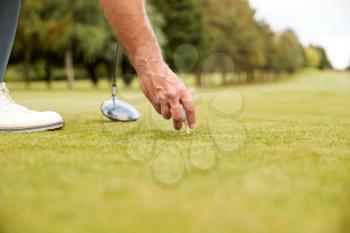 Close Up Of Mature Male Golfer Preparing To Hit Tee Shot Along Fairway With Driver