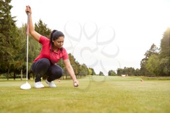 Female Golfer Preparing To Hit Tee Shot Along Fairway With Driver