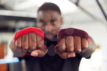 Portrait Of Male Boxer In Boxing Ring Training In Gym With Wraps On Hands