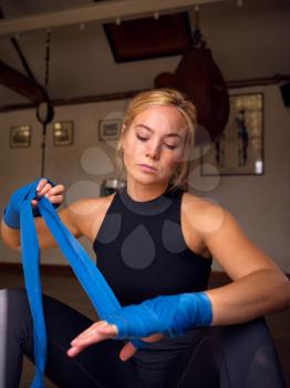 Female Boxer Training In Gym Putting Wraps On Hands