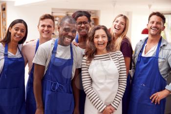 Portrait Of Smiling Group Of Students Wearing Aprons Taking Part In Cookery Class In Kitchen