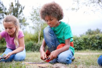 Two Children On Outdoor Camping Trip Learning How To Make Fire