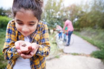 Girl Holding Small Frog As Group Of Children On Outdoor Activity Camp Catch And Study Pond Life