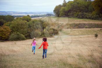 Rear View Of Group Of Children On Outdoor Activity Camping Trip Running Down Hill
