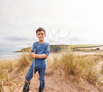 Portrait Of Boy Exploring Sand Dunes On Winter Beach Vacation