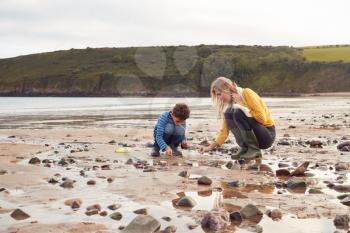 Family Looking In Rockpools On Winter Beach Vacation