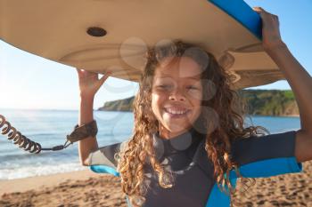 Portrait Of Smiling Girl Wearing Wetsuit Carrying Bodyboards On  Summer Beach Vacation