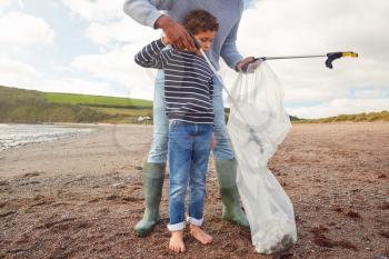 Father And Son Collecting Litter On Winter Beach Clean Up