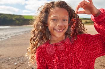 Portrait Of Smiling Girl Holding Seaweed On Winter Beach Vacation