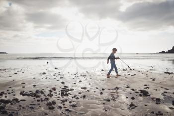 Young Boy Collecting Litter On Winter Beach Clean Up