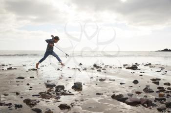 Young Boy Collecting Litter On Winter Beach Clean Up