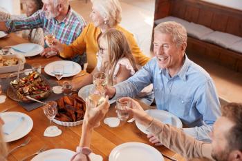 Multi-Generation Family Making A Toast With Wine As They Meet For Meal At Home