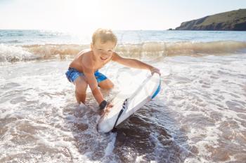 Boy Playing In Sea With Bodyboard On Summer Beach Vacation