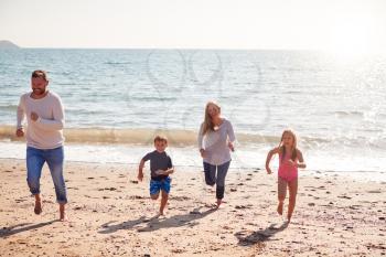 Family On Beach Running Across Sand Away From  Sea
