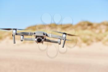 Drone With Camera Flying On Beach With Sand Dunes In Background