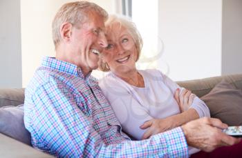 Senior Couple Relaxing At Home Sitting On Sofa Watching Television Together