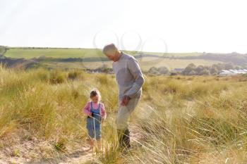 Grandfather And Granddaughter Collecting Litter On Winter Beach Clean Up