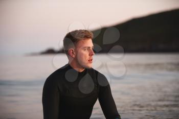 Man Wearing Wetsuit Sitting And Floating On Surfboard On Calm  Sea
