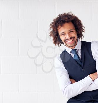 Portrait Of Confident Young Businessman Wearing Suit Standing Against White Studio Wall