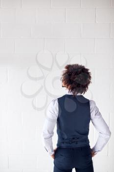 Rear View Of Young Businessman Wearing Suit Standing Against White Studio Wall