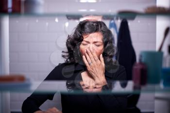 View Through Bathroom Cabinet Of Mature Businesswoman Yawning In Morning