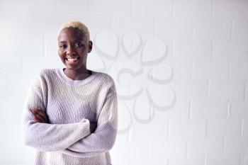Portrait Of Smiling Young Woman Standing Against White Studio Wall