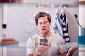 View Through Bathroom Cabinet Of Businessman Using Mobile Phone To Practise Presentation