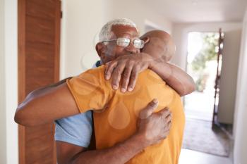 Loving Senior Father Hugging Adult Son Indoors At Home