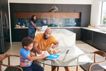 African American Father Helping Son Studying Homework In Kitchen