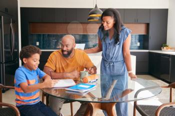 African American Parents Helping Son Studying Homework In Kitchen