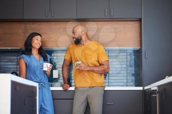 African American Couple Talking And Drinking Coffee In Kitchen At Home