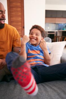 Loving African American Father And Son Sitting On Sofa At Home Together