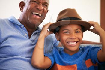 African American Grandfather And Grandson Family Sitting On Sofa With Boy Wearing Hat