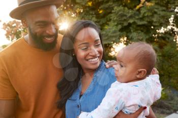Portrait Of African American Family With Baby Daughter Relaxing In Garden At Home Together