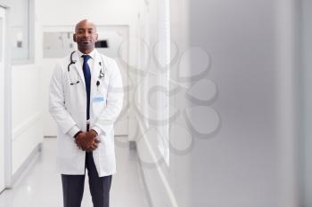 Portrait Of Mature Male Doctor Wearing White Coat Standing In Hospital Corridor