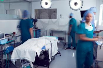 Motion Blur Shot Of Surgical Team Wearing Scrubs In Busy Hospital Operating Theater